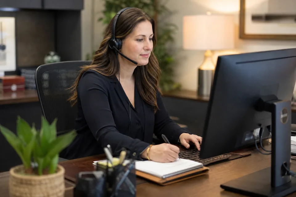 Law firm intake coordinator on a headset logging a new estate planning inquiry at her desk