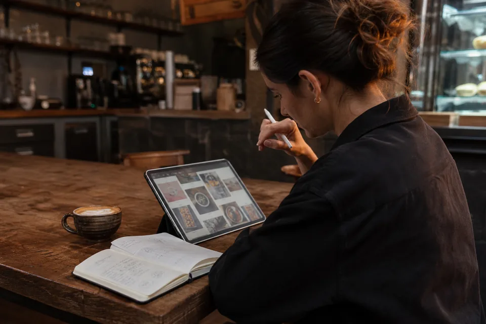 Cafe owner planning a month of social posts on a tablet at a table after closing